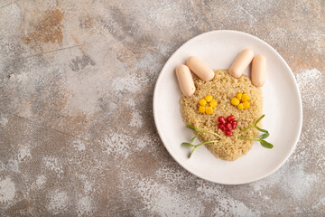 Funny quinoa porridge, and small sausages in form of cat face on brown concrete. top view, copy space.