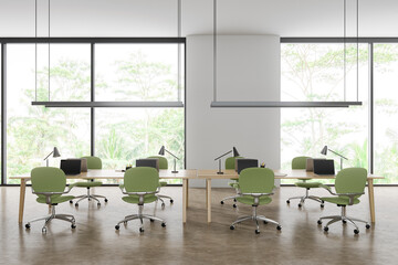 Stylish coworking interior with laptop on shared desk, panoramic window