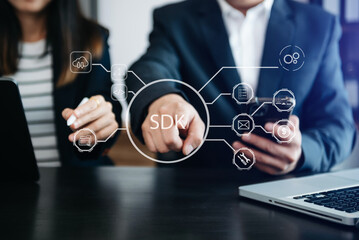 SDK  Software development kit programming language technology concept, Person typing laptop computer and tablet with SDK icon on virtual screen. in office