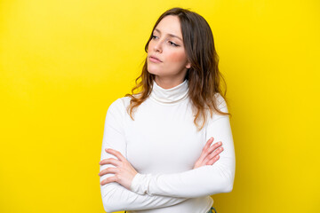 Young caucasian woman isolated on yellow background looking to the side