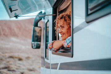 One female tourist enjoy view and freedom feeling inside a camper van vehicle looking outside the...