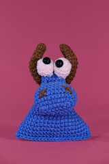 Amigurumi one small blue bull with brown horns on pink background. Soft DIY toy made of natural cotton and wool. Cows head crocheted, handmade art. Front view.