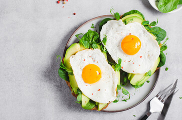 Avocado Sandwich with Fried Egg, Spinach and Green Sprouts, Healthy Breakfast or Snack on Bright Background