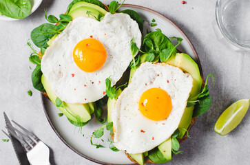 Avocado Sandwich with Fried Egg, Spinach and Green Sprouts, Healthy Breakfast or Snack on Bright Background