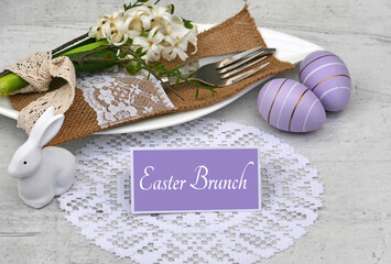 Set Easter table with a plate, cutlery, Easter eggs, flowers and a place card with the text Easter Brunch.