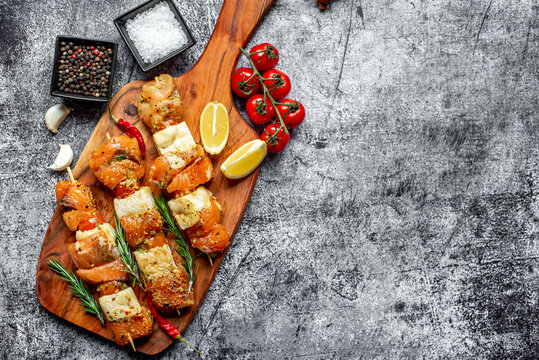  raw salmon skewers on skewers on a stone background with copy space for your text .Raw seafood on skewers