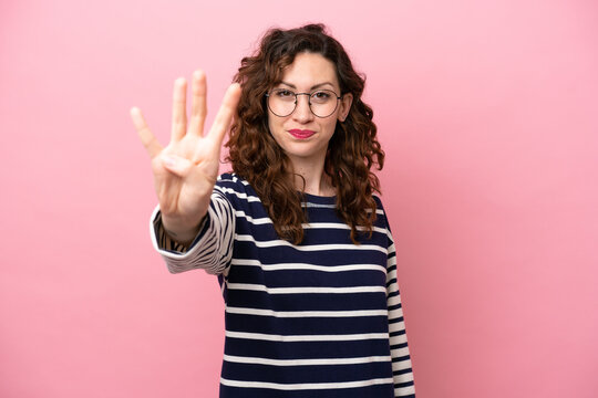 Young caucasian woman isolated on pink background happy and counting four with fingers