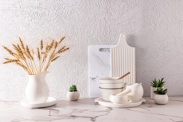 a set of modern white dishes and cutting boards on the kitchen white marble countertop. mintmalism in the interior of the kitchen.