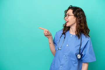 Young nurse caucasian woman isolated on blue background pointing finger to the side and presenting a product