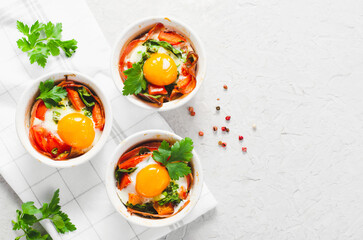 Baked Eggs with Bacon, Tomatoes, Spinach and Herbs on Bright Background, Healthy Breakfast or Snack