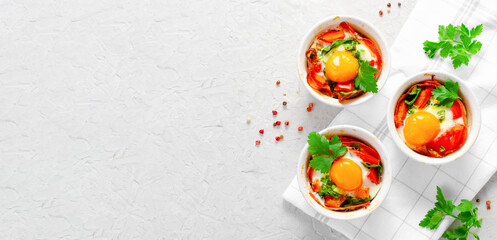 Baked Eggs with Bacon, Tomatoes, Spinach and Herbs on Bright Background, Healthy Breakfast or Snack