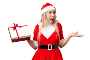 Young blonde woman with christmas hat and holding a gift over isolated chroma key background with surprise facial expression