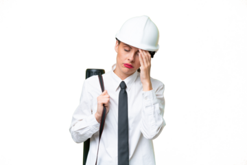 Young architect woman with helmet and holding blueprints over isolated background with headache