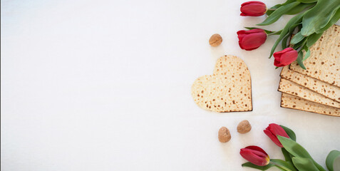 Fototapeta na wymiar white big banner Matzah shape of heart with red tulips and walnut on white background. Traditional of Holiday on Passover. Home symbol of lovely Jewish family in pesach. top view.