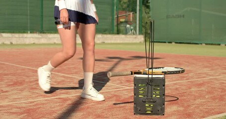 girl walking, pulling on her white socks , taking tennis ball from basket and racket, training day. slow motion close up cropped shot