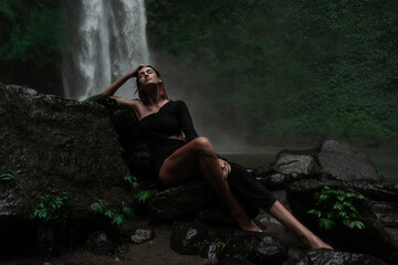Fototapeta na wymiar Young sexy woman posing at the waterfall in jungles. Ecotourism concept image travel girl