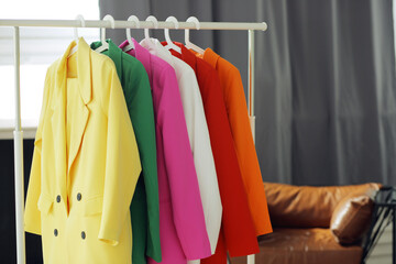 Multi-colored bright jackets on a hanger against the background of the room