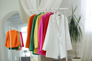 Multi-colored bright jackets on a hanger against the background of the room.