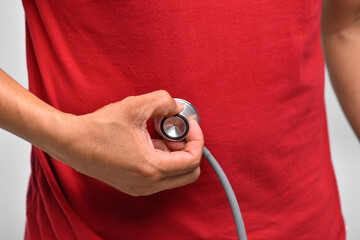 A doctor is using a stethoscope to examine the abdomen of a patient with severe abdominal pain.