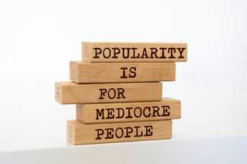 Wooden blocks with words 'Popularity is for Mediocre People'.