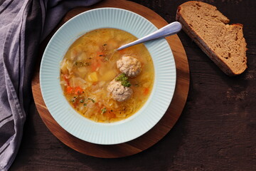Soup with meatballs on dark background, gray linen napkin. Healthy meatball soup with vegetables....