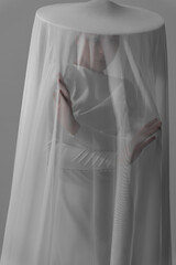woman under white veil posing sensually on white background