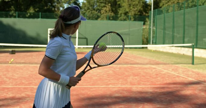 beautiful unexperienced female player is hitting the ball during the game , slow motion back view failure first steps of learning tennis, girl holding racket in hands