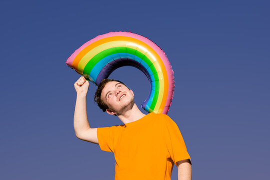 transgender man holding a rainbow balloon