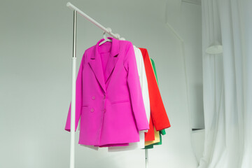 Multi-colored bright jackets on a hanger on a white background