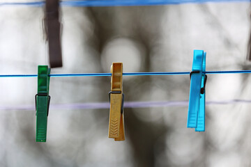Kolorowe spinacze do prania wiszą na sznurku do suszenia.  - obrazy, fototapety, plakaty