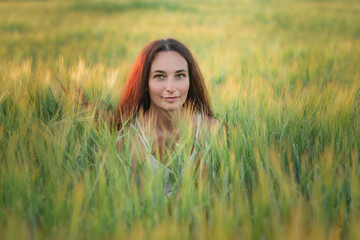 Portrait of a young beautiful dark-haired girl on a summer field in the evening.