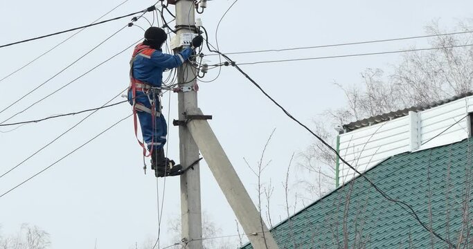 Electricity. An electrician installs an electric energy meter by climbing an electric pole.