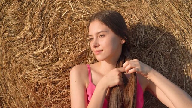Rural girl braids a braid of hair near haystack