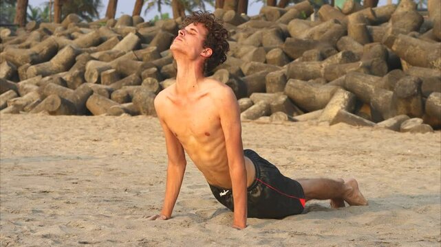 Man doing yoga on the sandy beatch