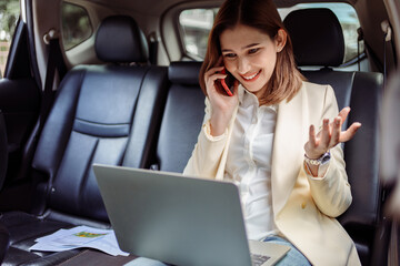 Businesswoman talking on the mobile phone and using the laptop in the car.