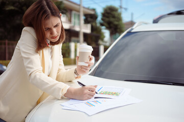 Busy woman is in a hurry, she does not have time, she is going to talk on the phone on the go. Businesswoman doing multiple tasks On the hood of the car. Multitasking business person.