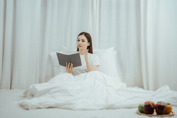 Happy woman holding apple and listening to music sitting on sofa in living room at home