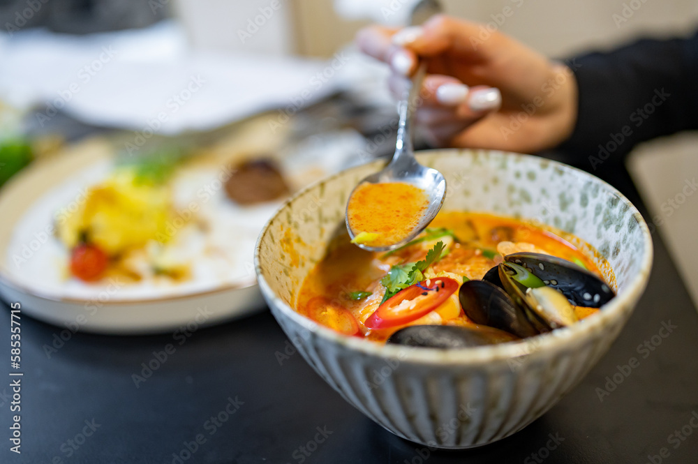 Poster woman eating thai tom yam soup in a restaurant