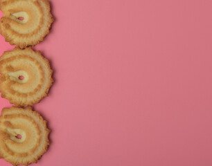 Ciastka na różowym tle ułożone po lewej stronie zdjęcia 