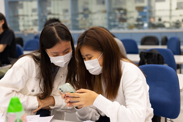 group of happy young boys and girls with face mask work, discuss, study on assignment and teaching materials together in classroom in university in Hong Kong during covid-19