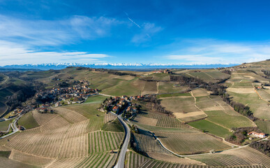 hilly countryside in the Italian Piedmont with the village of Barolo and snow-covered mountains...