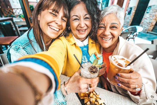 Happy Senior Women Drinking Cocktail Glasses Sitting At Bar Table - Group Of Best Friends Enjoying Happy Hour Cheering Drinks At Pub Restaurant - Life Style Concept With Girls Hanging Out Together