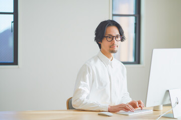 パソコンに向かってタイピングをする若い男性