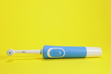 Modern electric toothbrush on yellow background