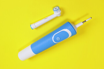 electric toothbrush and toothbrush head on yellow background, concept of oral hygiene, dental care