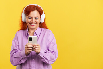 Mature woman listening to music with headphones and a mobile