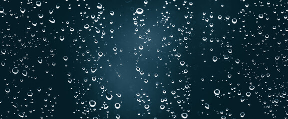Fototapeta premium Atmospheric minimal monochrome backdrop with rain droplets on glass. Wet window with rainy drops and dirt spots closeup. Blurry minimalist background of dirty window glass with raindrops close up.