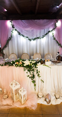A beautifully set wedding table at a banquet with lanterns, candles and other decorations for the newlyweds. Creative image for your design or illustrations.