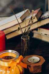 Still life with skins, Orange aroma candle in a figured candlestick with a bow and books on the background.