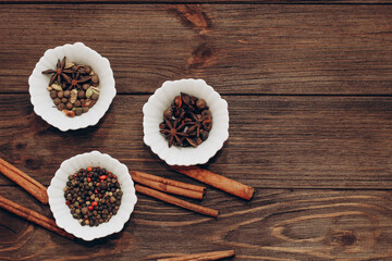 Spices anise, pepper, cumin, cumin, ginger in bowls on a wooden table.